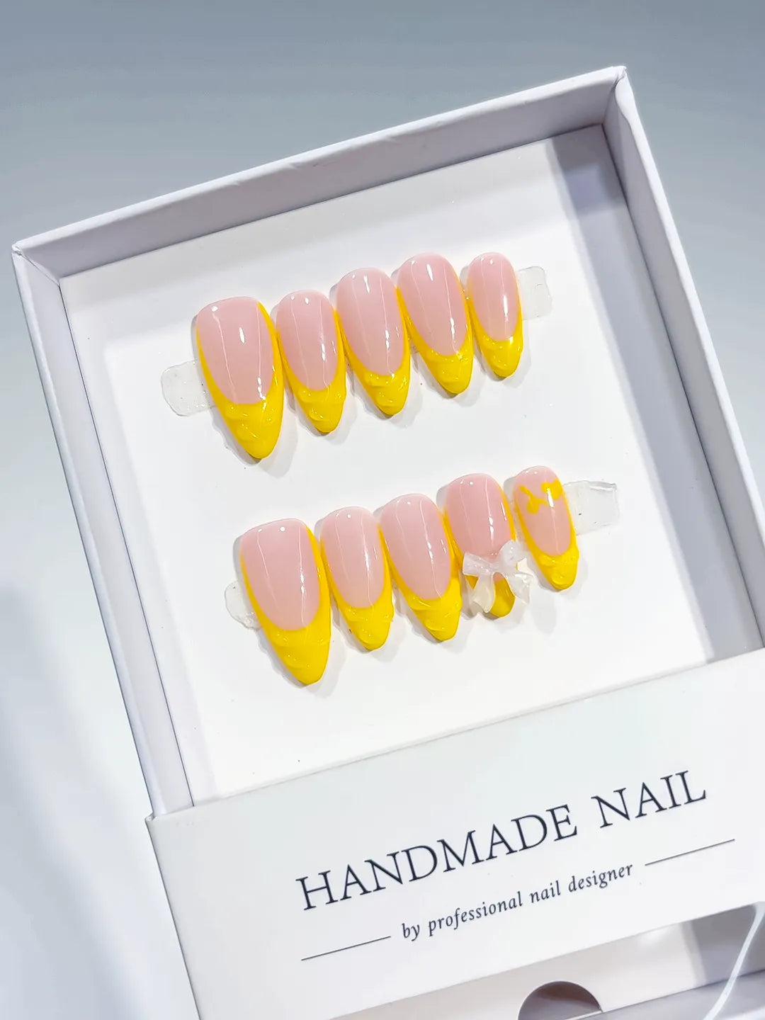Nude Yellow French tip Bow press on nails angled view