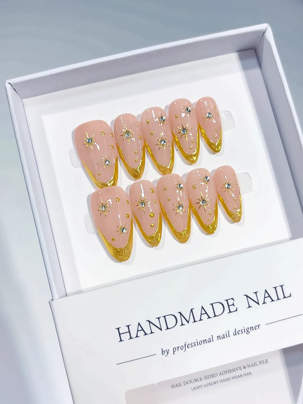 Medium almond set with nude base, gold French V-tips and rhinestone star accents handmade press on nails