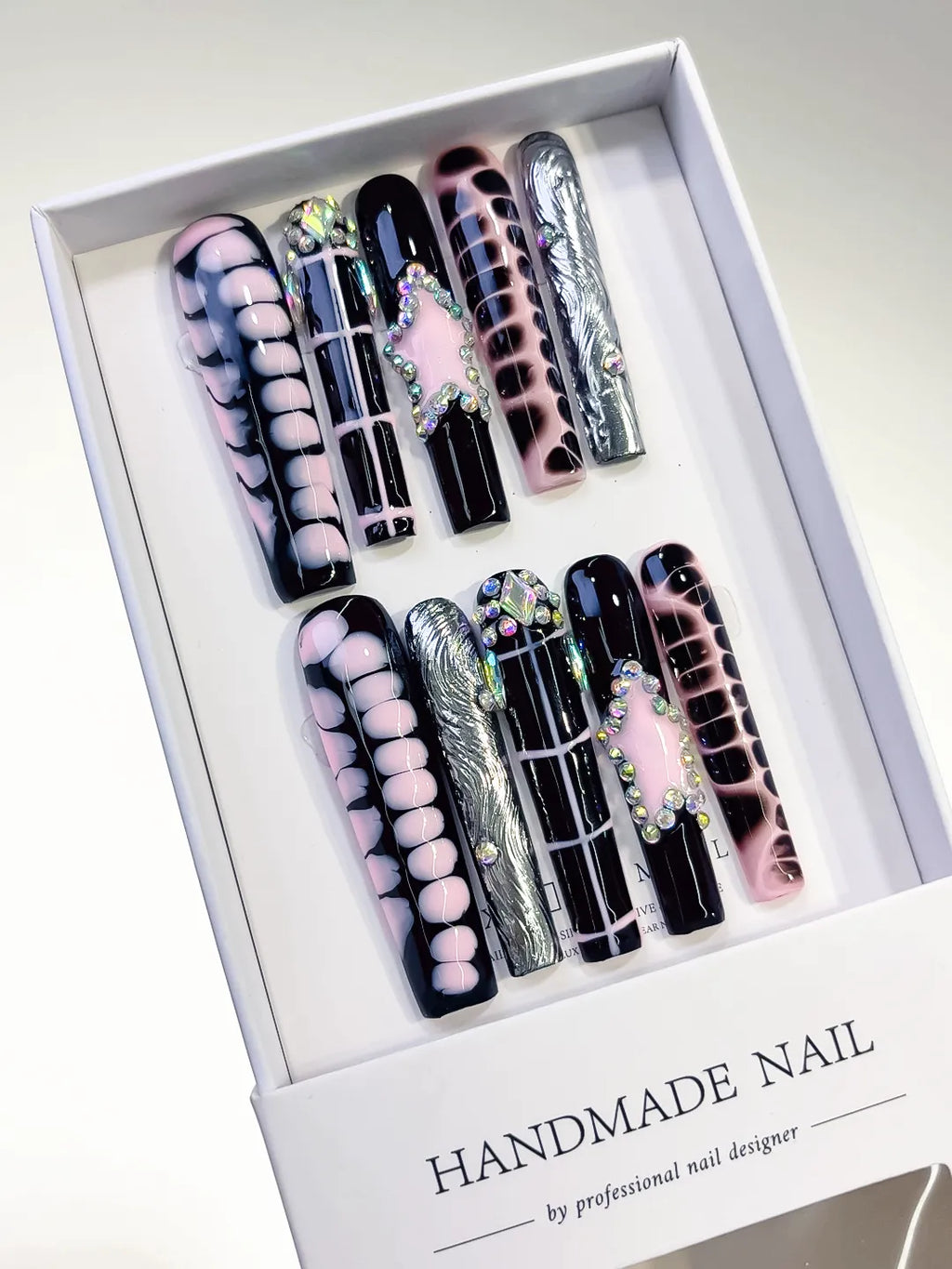handmade press on nails set in long square black and pink with chrome accents and 3D rhinestone frame centerpiece