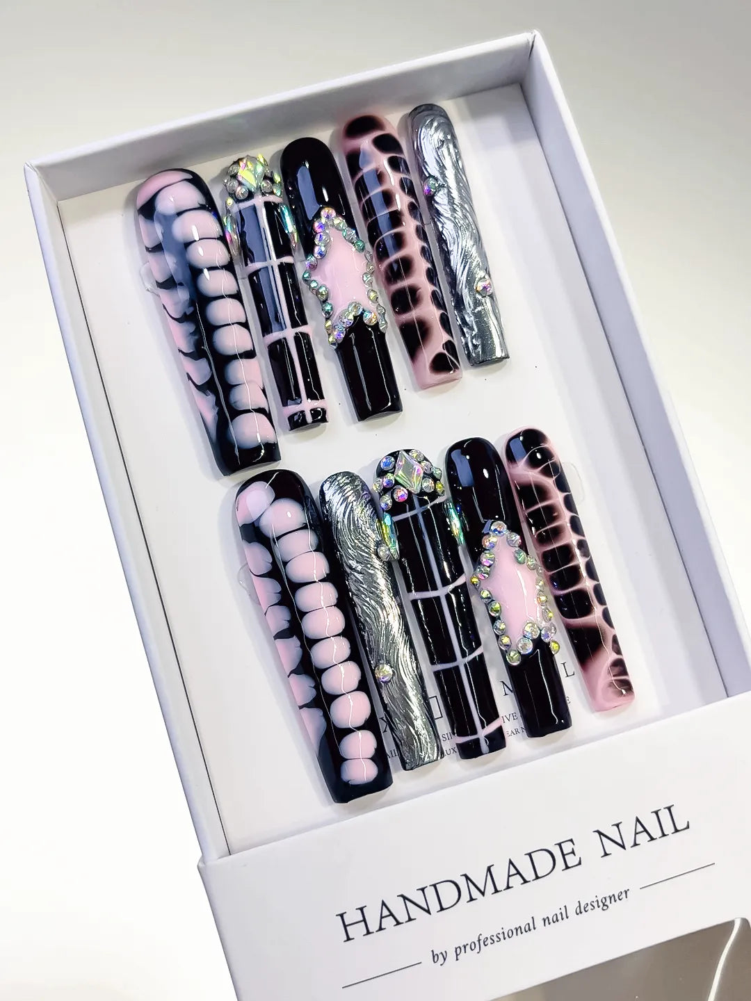handmade press on nails set in long square black and pink with chrome accents and 3D rhinestone frame centerpiece